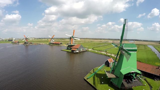 Aerial hoover close to green windmill in background showing rest of Zaanse Schans one of most popular tourist attractions Netherlands Holland near Amsterdam sustainable energy drone bird-eye view 4k