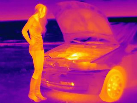 Thermal image of woman looking at automobile engine on roadside