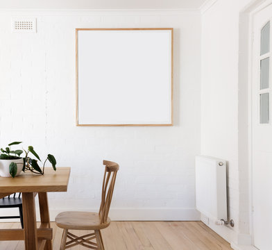Blank framed print on white wall in danish styled interior dinin