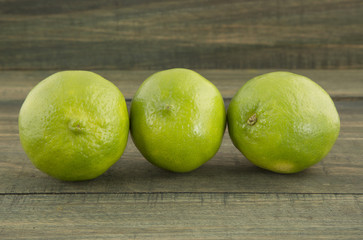 Green lemons on wooden table