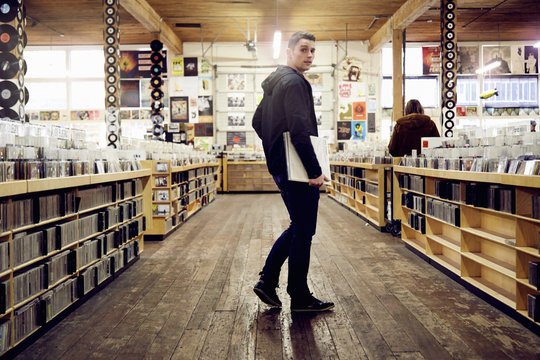 Young man holding vinyl record in music store