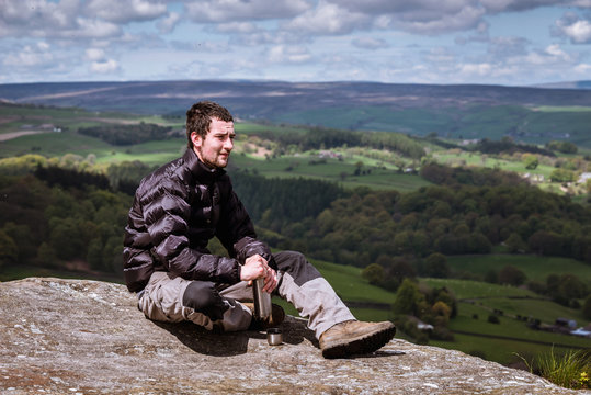 Young male hiker opening flask on top of Guise Cliff, Pateley Bridge, Nidderdale, Yorkshire Dales