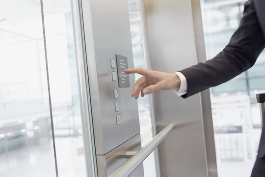 Hand of businessman pressing control in elevator