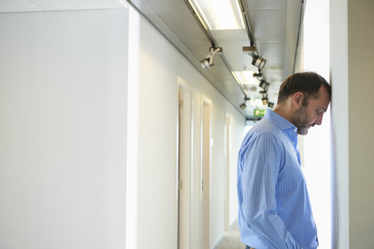 Mature man leaning head against wall in corridor