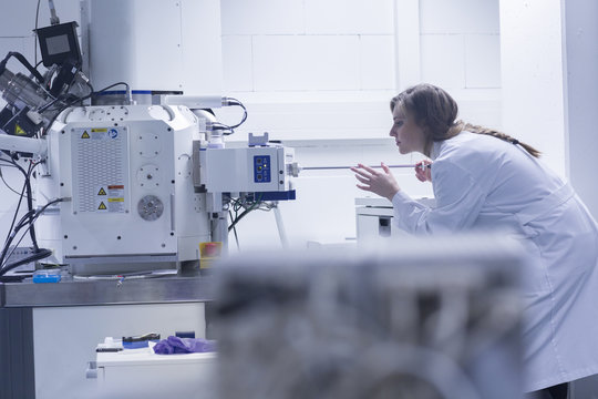 Young female scientist in lab using scanning electron microscope