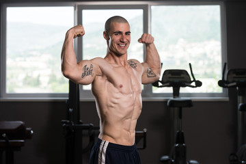 Biceps Pose Of A Young Man In Gym