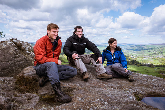 Male and female hikers sitting on top of Guise Cliff, Pateley Bridge, Nidderdale, Yorkshire Dales