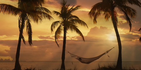 Young woman reclining on hammock at sunset on Miami Beach, Florida, USA