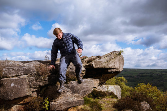 Male teenage hiker stepping down rocks on Guise Cliff, Pateley Bridge, Nidderdale, Yorkshire Dales