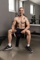 Fototapeta na wymiar Attractive Young Man Resting In Gym Afther Exercise