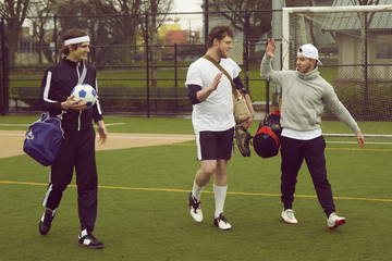 Three male soccer players walking and talking on soccer pitch