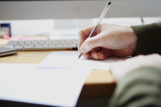 Man Writing On Paper With Pen