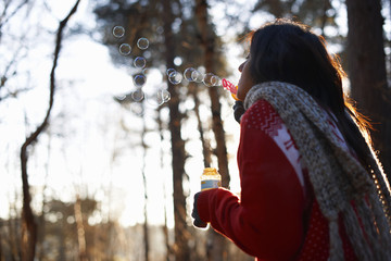 Mature woman blowing bubbles in forest
