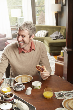 Young Man Eating Breakfast In Kitchen