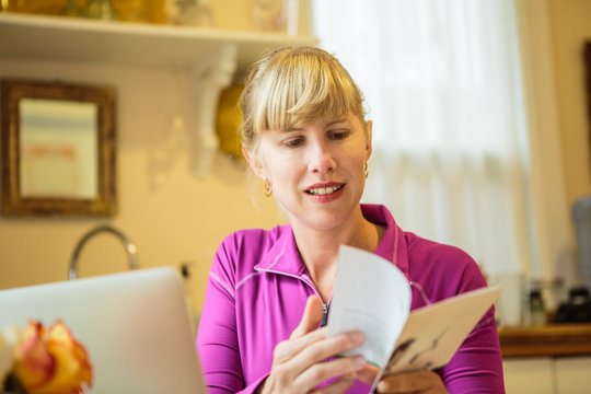 Woman working in kitchen table reading instruction booklet