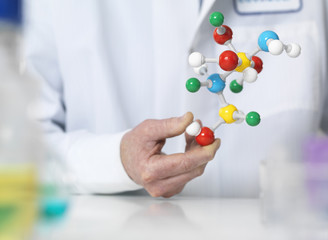 Scientist holding a molecular model of a chemical formula
