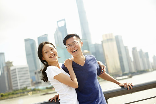 Tourist couple smiling on bridge, The Bund, Shanghai, China