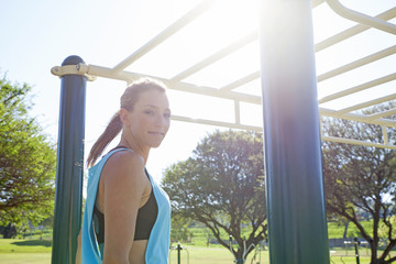 Mid adult woman preparing to train on monkey bars in park