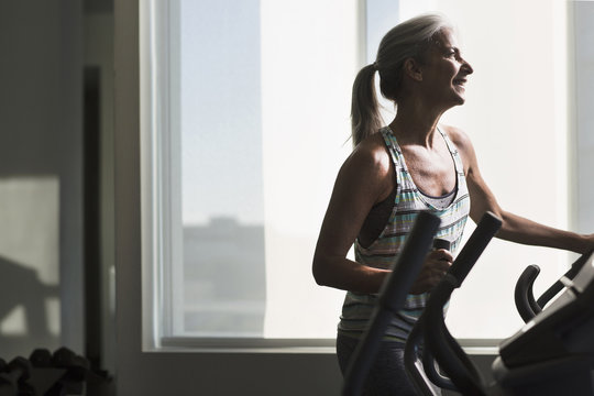 Mature woman exercising on gym machine