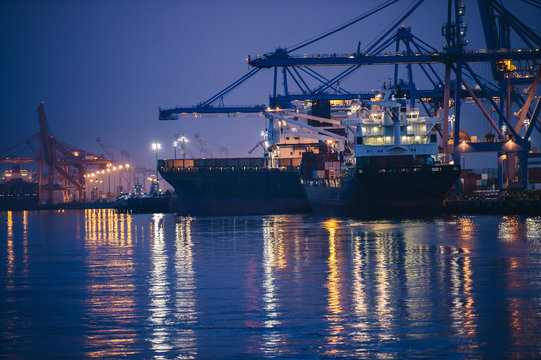 View of cargo ships and gantry cranes in harbor at night, Tacoma, Washington, USA