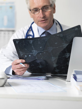 Doctor studying film sheet of computed tomography (CT) scans of various sections through the human head