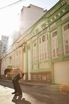 Man balancing ball on back in street