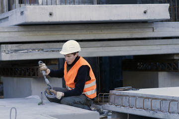 Factory worker attaching hook to concrete block in concrete reinforcement factory