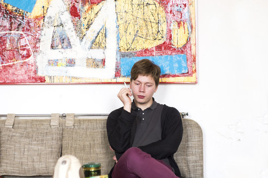 Male artist smoking cigarette whist sitting on studio sofa