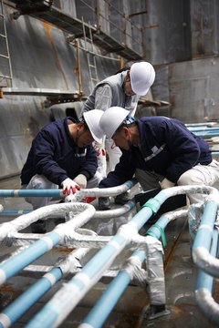 Workers checking pipework on container ship at shipyard, GoSeong-gun, South Korea