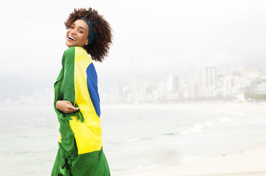 Portrait of young woman wrapped in Brazilian flag on Ipanema beach, Rio De Janeiro, Brazil