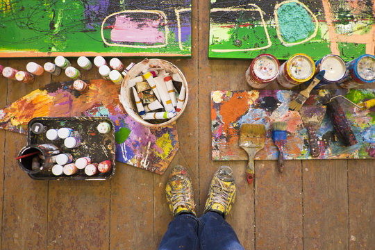 Artist selfie of feet paints and abstract painting in studio