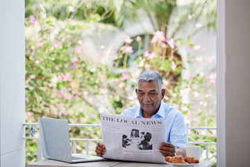 Senior Indian businessman reading newspaper in the morning