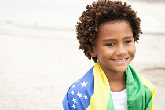 Boy wrapped up in Brazilian flag on Ipanema beach, Rio De Janeiro, Brazil