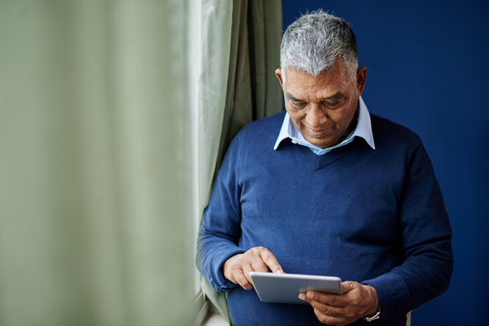 Indian elderly man using application on digital tablet