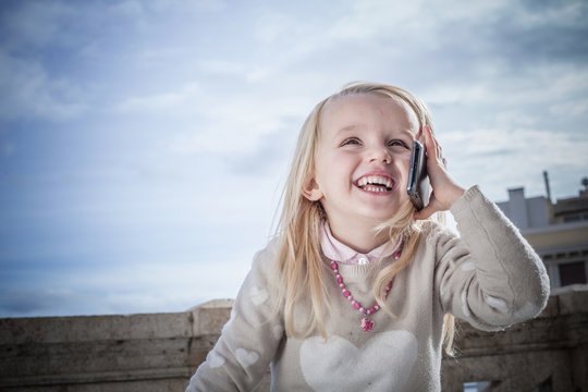 Young girl laughing and chatting on smartphone, Cagliari, Sardinia, Italy
