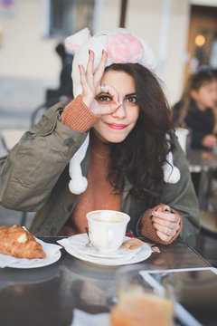 Portrait of  young woman making ok hand gesture at sidewalk cafe