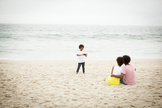 Couple and son taking photograph on beach