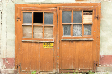 Old barn door with broken glass and sign – German Translation „Keep entrance free“
