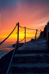 Obraz premium Stairways in rock over sea at sunset