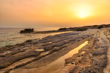 Cyprus rocky beach at golden sunset in Mediterranean sea 