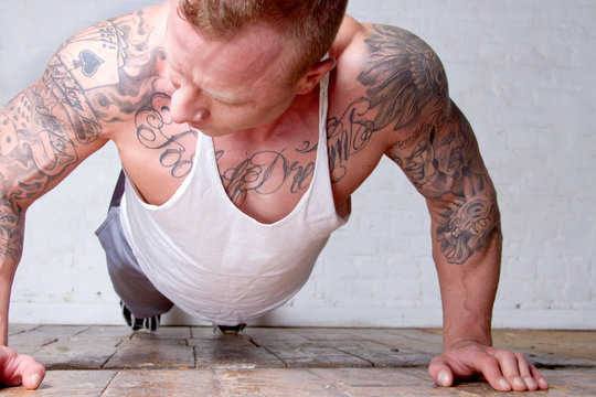 Young man with tattoos doing press ups