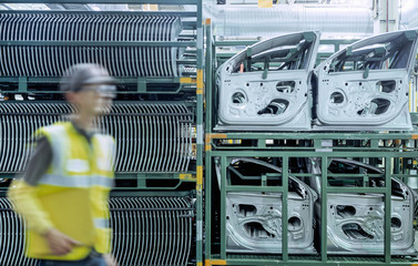 Worker passing car door parts in car factory