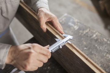 Carpenter measuring wood plank with vernier caliper in factory, Jiangsu, China