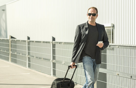 Mature man pulling wheeled suitcase