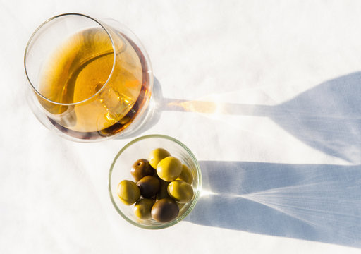 Brandy glass and olives on sunlit table