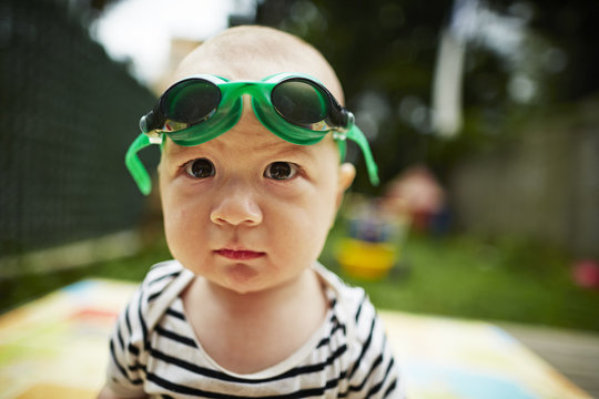 Close up portrait of baby boy looking at camera wearing swimming goggles