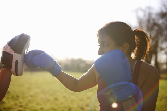 Mature woman boxer training in field