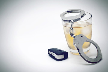 Car key with glass of whiskey and handcuffs - drive under influence concept