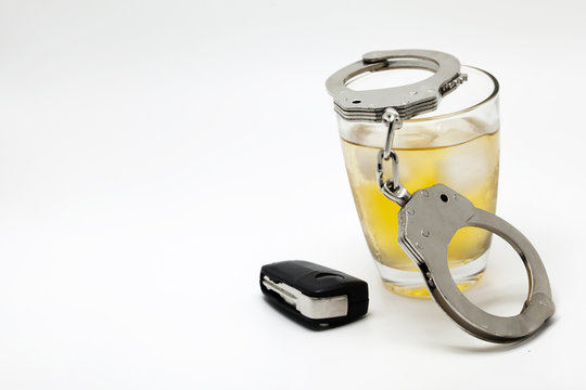 Car key with glass of whiskey and handcuffs - drive under influence concept