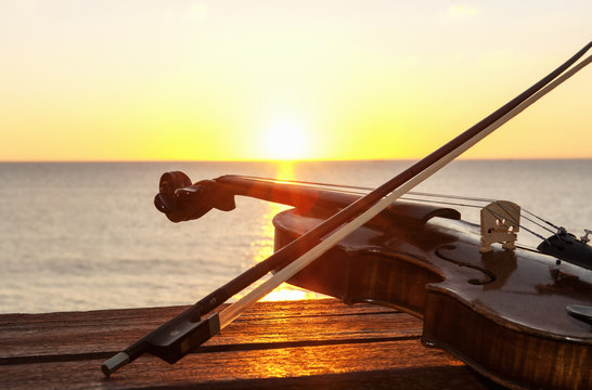 Sunset over sea with violin and bow on bench